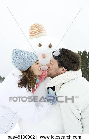 Young couple leaning towards each other in front of snowman, smiling, portrait View Large Photo Image Stock Image - Young couple leaning towards each other in front of snowman, smiling, portrait. Fotosearch