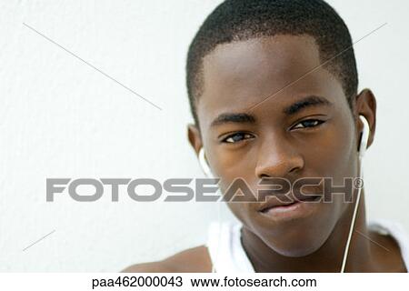 Teenage boy listening to earphones, looking at camera, portrait View Large Photo Image Stock Image - Teenage boy listening to earphones, looking at camera, portrait. Fotosearch