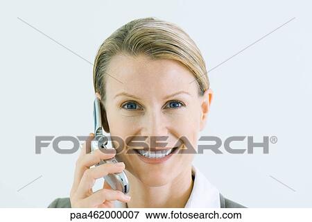 Stock Photo - Woman using cell phone, smiling at camera, portrait. Fotosearch