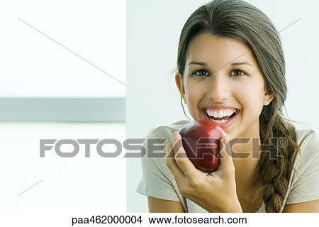Young female holding apple, smiling at camera, portrait View Large Photo Image Picture - Young female holding apple, smiling at camera, portrait. Fotosearch