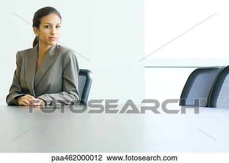 Young female in business suit sitting at table, looking at camera, portrait View Large Photo Image Stock Image - Young female in business suit sitting at table, looking at camera, portrait. Fotosearch