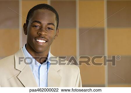 Stock Image - Young male dressed in business attire smiling at camera, portrait. Fotosearch