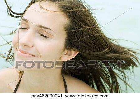 Young woman smiling, eyes closed, hair blowing in breeze, portrait View Large Photo Image Stock Image - Young woman smiling, eyes closed, hair blowing in breeze, portrait. Fotosearch