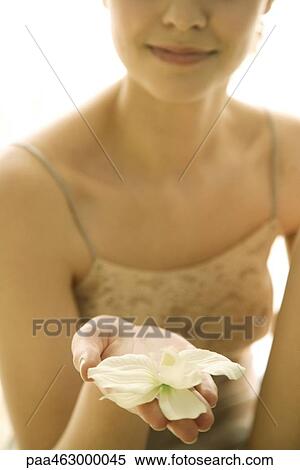 Stock Photography - Female holding out orchid flower on palm of hand, cropped. Fotosearch
