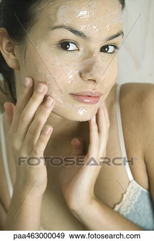 Young woman putting exfoliant mask on face, smiling at camera View Large Photo Image Stock Photo - Young woman putting exfoliant mask on face, smiling at camera. Fotosearch