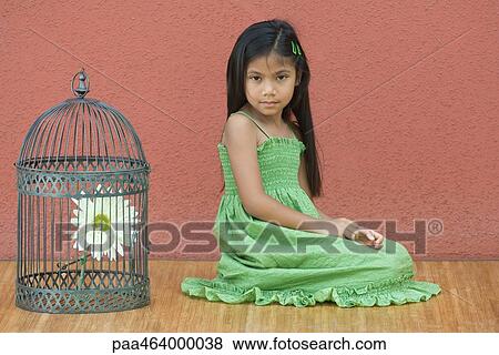Girl in sundress kneeling on floor, looking at camera, next to birdcage containing flower View Large Photo Image Stock Photo - Girl in sundress kneeling on floor, looking at camera, next to birdcage containing flower. Fotosearch