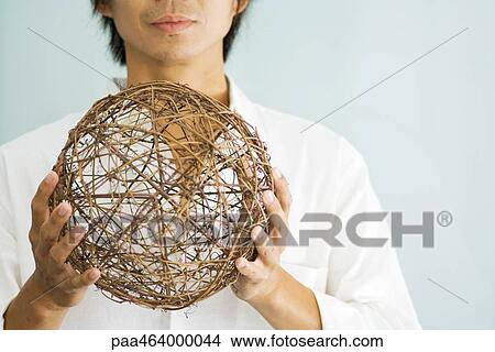 Man holding up wicker sphere, cropped view View Large Photo Image Picture - Man holding up wicker sphere, cropped view. Fotosearch