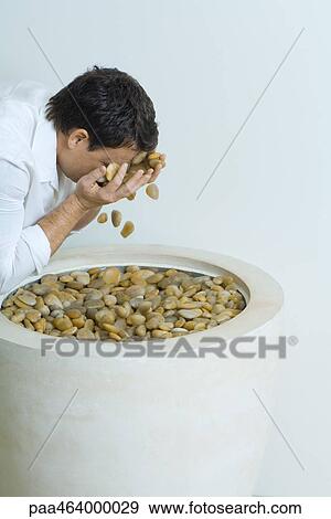 Stock Photo - Man splashing face with pebbles, cropped, side view. Fotosearch