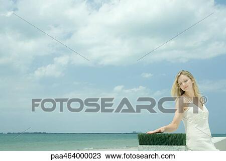 Woman sitting near sea, touching blades of wheat grass View Large Photo Image Stock Image - Woman sitting near sea, touching blades of wheat grass. Fotosearch