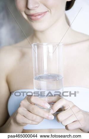 Cropped view of woman holding glass of water, smiling View Large Photo Image Picture - Cropped view of woman holding glass of water, smiling. Fotosearch