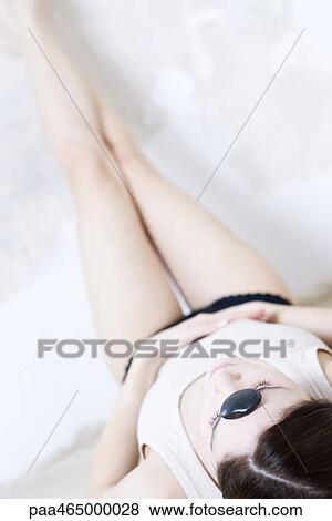 Woman lying on back with legs up, rock on forehead View Large Photo Image Stock Photo - Woman lying on back with legs up, rock on forehead. Fotosearch