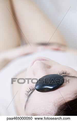 Woman lying on back with pebble on forehead, eyes closed View Large Photo Image Stock Image - Woman lying on back with pebble on forehead, eyes closed. Fotosearch
