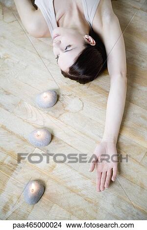 Woman lying on the ground with candles, arm raised, looking away View Large Photo Image Picture - Woman lying on the ground with candles, arm raised, looking away. Fotosearch
