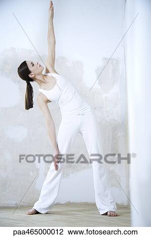 Stock Image - Woman standing, doing yoga pose, full length. Fotosearch