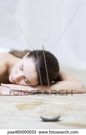 Woman with head resting on arms, eyes closed, incense burning in foreground View Large Photo Image Stock Image - Woman with head resting on arms, eyes closed, incense burning in foreground. Fotosearch