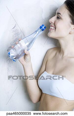 Young woman holding up water bottle, smiling, profile View Large Photo Image Stock Photography - Young woman holding up water bottle, smiling, profile. Fotosearch