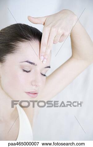 Stock Photo - Young woman touching forehead, eyes closed. Fotosearch