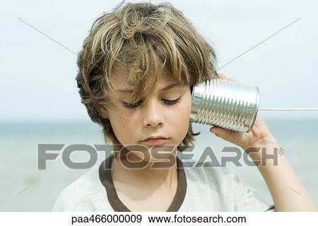 Boy listening to tin can phone, looking down, portrait View Large Photo Image Stock Photo - Boy listening to tin can phone, looking down, portrait. Fotosearch