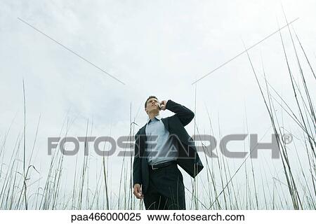 Man standing in tall grass, using cell phone, low angle view View Large Photo Image Stock Photography - Man standing in tall grass, using cell phone, low angle view. Fotosearch