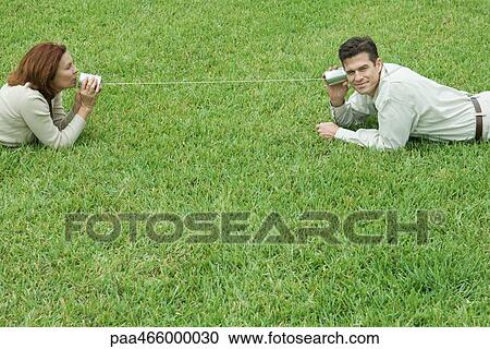 Mature couple lying on the ground, talking to each other through tin can phone View Large Photo Image Stock Image - Mature couple lying on the ground, talking to each other through tin can phone. Fotosearch