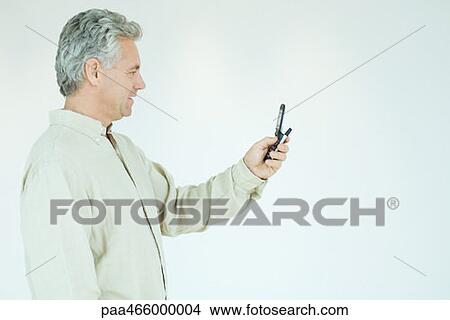 Picture - Mature man looking at cell phone, side view. Fotosearch