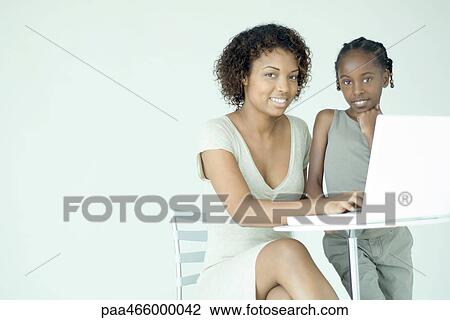 Mother and daughter using laptop computer together, smiling at camera View Large Photo Image Stock Image - Mother and daughter using laptop computer together, smiling at camera. Fotosearch