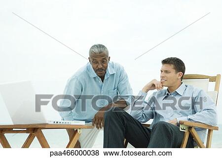Stock Photo - Two businessmen looking at laptop computer together outdoors. Fotosearch