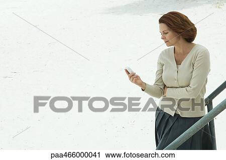 Woman looking down at cell phone, arms folded View Large Photo Image Stock Image - Woman looking down at cell phone, arms folded. Fotosearch