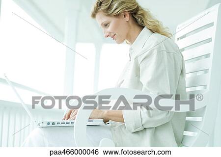 Woman sitting on porch, using laptop computer, smiling View Large Photo Image Stock Photograph - Woman sitting on porch, using laptop computer, smiling. Fotosearch