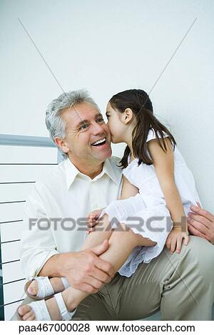 Stock Photo - Little girl sitting on mature man's lap, kissing his cheek. Fotosearch