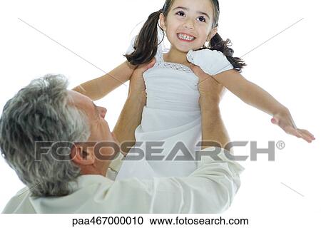 Stock Image - Mature man lifting up little girl into the air. Fotosearch