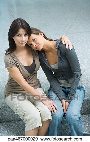 Stock Photo - Mother and teenage girl sitting side by side, teen girl resting head on woman's shoulder. Fotosearch