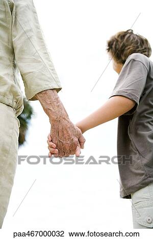 Stock Image - Senior woman and grandson holding hands, cropped, low angle view. Fotosearch