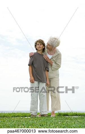 Senior woman and grandson standing on grass, woman talking to boy over his shoulder, full length View Large Photo Image Stock Image - Senior woman and grandson standing on grass, woman talking to boy over his shoulder, full length. Fotosearch
