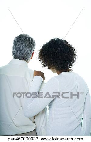 Stock Image - Young woman with hand on mature man's shoulder, rear view, waist up. Fotosearch