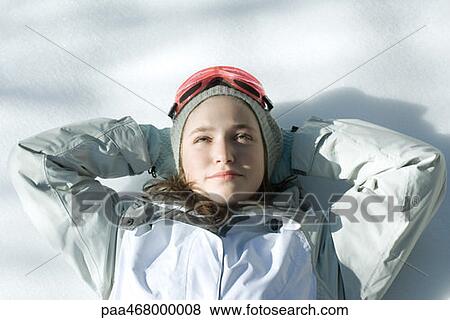 Stock Photo - Teen girl lying on snow with hands behind head, head and shoulders. Fotosearch