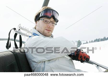 Young male skier taking ski lift View Large Photo Image Stock Photo - Young male skier taking ski lift. Fotosearch
