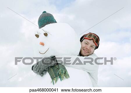 Young man hugging snowman, low angle view View Large Photo Image Stock Image - Young man hugging snowman, low angle view. Fotosearch