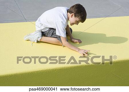 Stock Image - Boy on knees, bending forward, about to flick bug, full length. Fotosearch