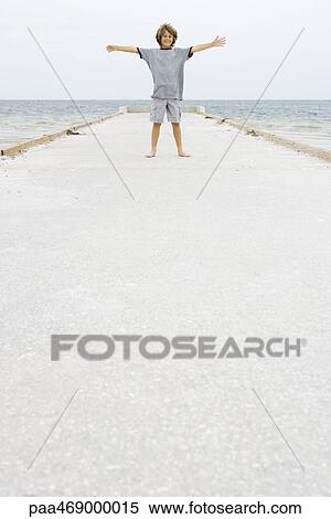 Boy standing on pier with arms out, smiling at camera, full length, front view View Large Photo Image Stock Photography - Boy standing on pier with arms out, smiling at camera, full length, front view. Fotosearch