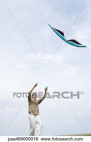 Man flying kite, low angle view View Large Photo Image Stock Photograph - Man flying kite, low angle view. Fotosearch