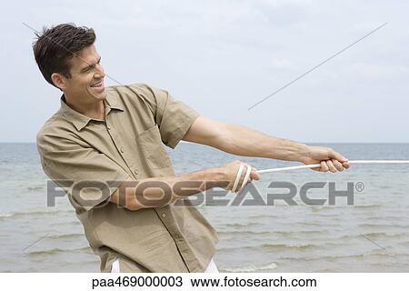 Man pulling rope, smiling, ocean in background, waist up View Large Photo Image Stock Image - Man pulling rope, smiling, ocean in background, waist up. Fotosearch
