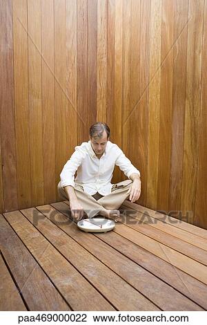 Man sitting with legs crossed on wooden floor, looking down at miniature rock garden, full length View Large Photo Image Stock Image - Man sitting with legs crossed on wooden floor, looking down at miniature rock garden, full length. Fotosearch