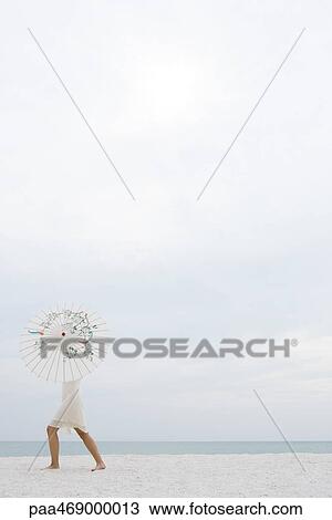 Woman standing on beach, upper body hidden by parasol, full length, side view View Large Photo Image Stock Image - Woman standing on beach, upper body hidden by parasol, full length, side view. Fotosearch