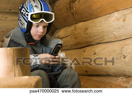 Stock Photography - Boy in ski gear using cell phone. Fotosearch