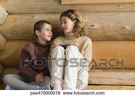 Stock Photo - Teen girl playing video game, next to preteen boy. Fotosearch