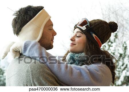 Young couple in winter clothing, woman with arms around man's neck, side view View Large Photo Image Stock Photograph - Young couple in winter clothing, woman with arms around man's neck, side view. Fotosearch