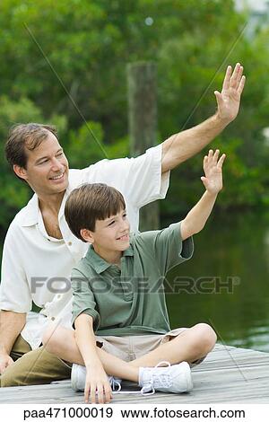 Father and son sitting on dock and waving together View Large Photo Image Stock Photo - Father and son sitting on dock and waving together. Fotosearch