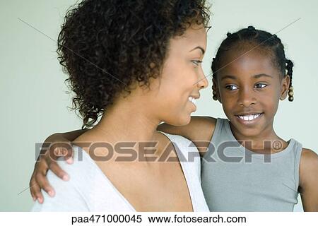 Mother holding daughter, both smiling and looking away, close-up View Large Photo Image Stock Photography - Mother holding daughter, both smiling and looking away, close-up. Fotosearch