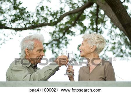 Senior couple making a toast with champagne outdoors View Large Photo Image Stock Photo - Senior couple making a toast with champagne outdoors. Fotosearch